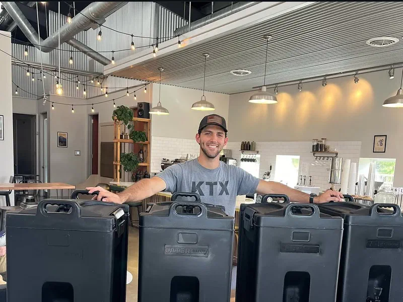 A barista with insulated coffee dispensers ready for an office delivery