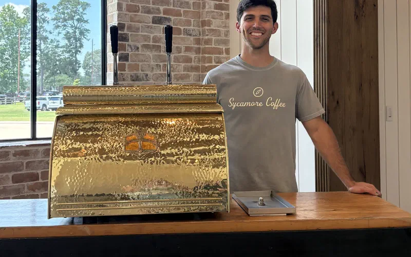A barista serving drinks from the Sycamore coffee cart